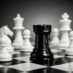 Torre negra de ajedrez goteando petróleo entre piezas blancas, símbolo del poder geopolítico y la fragilidad económica global